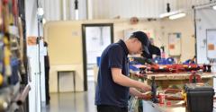 Man in cap working on bench with pipes in workshop