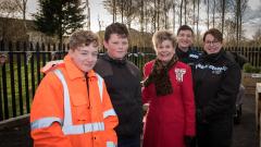 Two young students pose with the Mayor and two police officers, against fence,and woodland backdrop