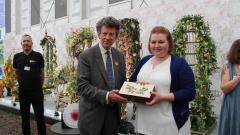 Rebecca Hough receiving Chelsea Flower Show Medal from a man in a grey suit