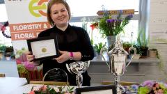 Rebecca Hough posing with trophies and holding a framed certificate