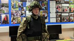 A student wearing army camouflage gear and donated tactical vest