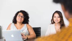 Three people in a meeting with a laptop