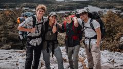 A group photo of students wearing backpacks in the wilderness