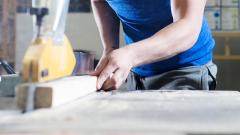 Close up of a person using a lathe to cut a piece of timber