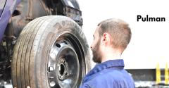 A photo of a man with a beard fitting a vehicle tyre. The word Pulman is behind him