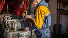 Man in yellow overalls working on a tractor engine