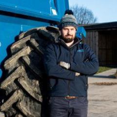 Man stood in front of tractor wheel