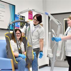 Health &amp; Social student sat in hoist being lifted by other students