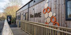 Wooden building with 'The Hive' logo on the side and hexagon designs