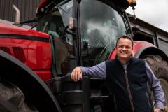 Graham Wilkinson stood smiling in front of a red tractor