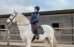 Izzy Sherrington smiling sat on a white horse